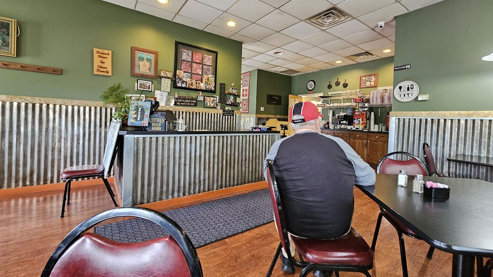 The dining room: green walls, corrugated tin wainscot, red chairs and family photos by the counter
